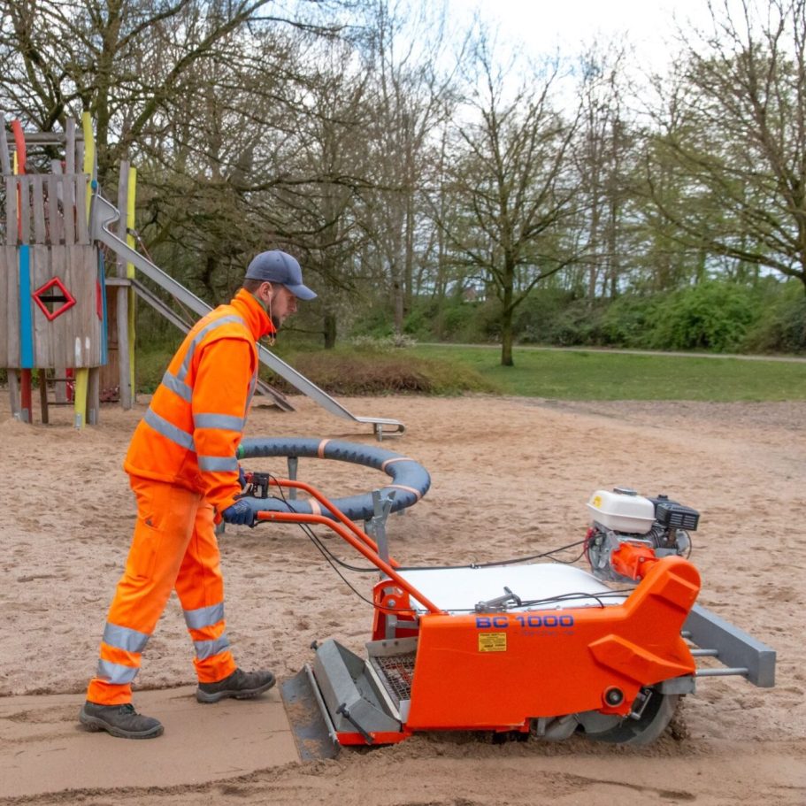 Spielplatzreinigung mit dem Sandreiniger BC1000 auf dem Spielplatz Sandreiniger BC1000 bei der Sandreinigung auf einem Spielplatz. Der Sandreiniger wird von nur einer Person bedient .